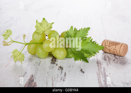 Bottiglia di vino i tappi di sughero e foglie di uva isolato su bianco sullo sfondo di legno. Foto Stock