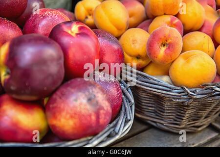Le pesche noci e le albicocche in cesti di vimini al mercato Foto Stock