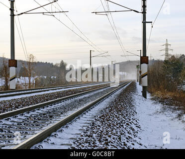 Snowy linea ferroviaria con sovraccarico elettrico cablaggio Foto Stock