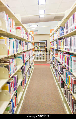 Una vista di scaffali di libri e di un area di studio all'interno di una biblioteca moderna. Foto Stock