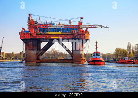 Oil Rig in compagnia di un rimorchiatore barche entra in un porto. Foto Stock