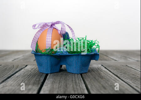 Uovo in un nido di pasqua su un tavolo. Foto Stock