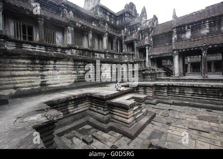 Giovane turista medita da una piscina in un cortile interno di Angkor Wat, Cambogia Foto Stock