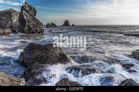 Onde che si infrangono su una costa rocciosa Foto Stock