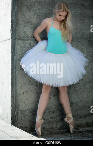 Leggiadra danzatrice con capelli biondi sullo sfondo di grigio concre Foto Stock