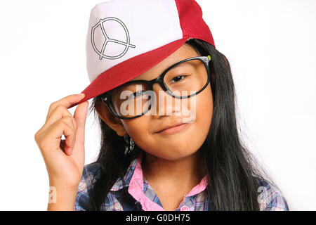 Bambina con gli occhiali sorridente e toccando il suo cappello isolato su bianco Foto Stock