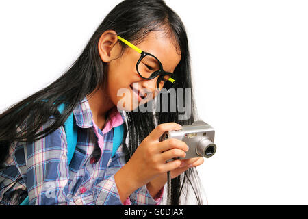 Poco ragazza sorridente mentre prendere foto con la sua fotocamera isolato su bianco Foto Stock