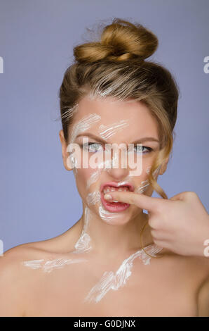 La donna nel dentifricio sul corpo pulisce i denti del dito Foto Stock