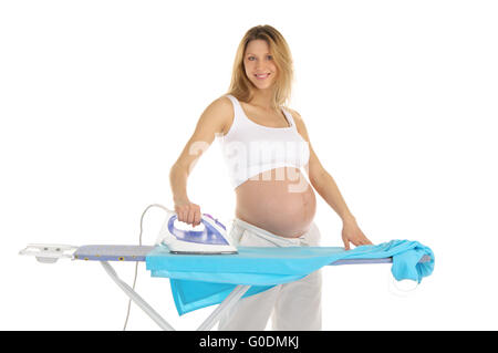 Donna incinta in un abito bianco con un ferro da stiro Foto Stock