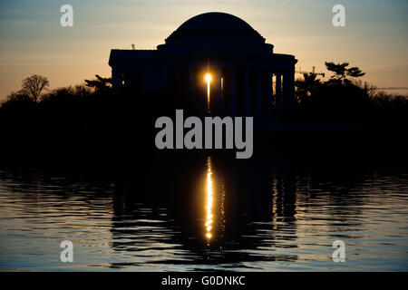 WASHINGTON, D.C., Stati Uniti: Il Jefferson Memorial è caratterizzato da una spettacolare sagoma contro il sole che sorge sul bacino delle maree di Washington, D.C. questa vista iconica cattura la caratteristica cupola e colonnato del monumento neoclassico in netto contrasto con la luce dorata dell'alba. Foto Stock