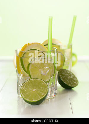 Un bicchiere di acqua con tigli e fette di limone Foto Stock