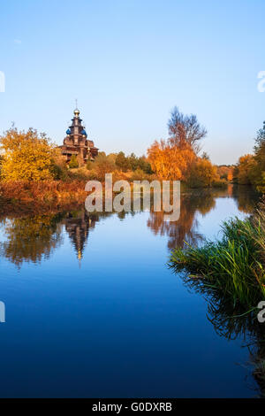 Paesaggio con una chiesa in legno sopra il fiume Foto Stock