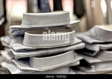 Mens Dress shirt impilati sul ripiano in department store con cravatte in background Foto Stock