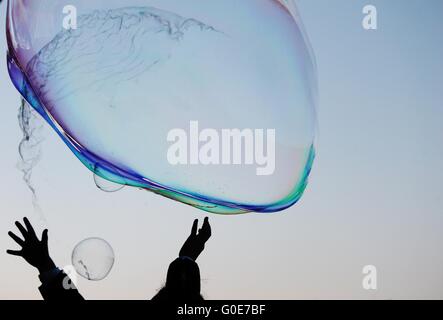 Le mani per sognante bolle di sapone galleggiante sul th Foto Stock