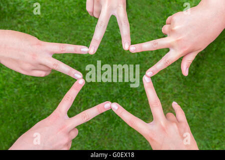 Le mani di ragazze messa a forma di stella al di sopra di erba Foto Stock