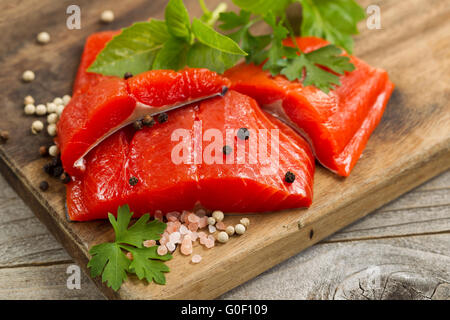 Carni di colore rosso brillante fiume di rame i filetti di salmone su legno rustico server con erbe e spezie Foto Stock