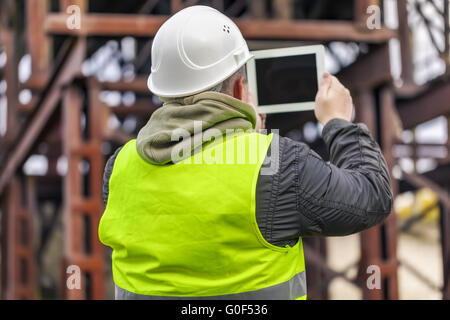 Ingegnere girato cisterne con il tablet PC in fabbrica Foto Stock