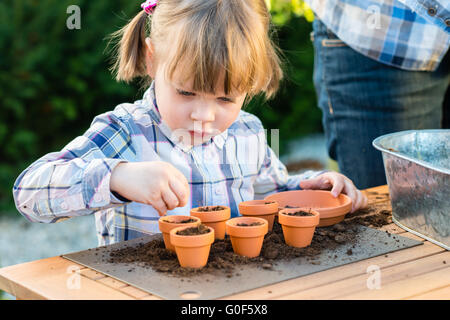 Ragazza di piantare semi di fiori in vasi con sua madre Foto Stock