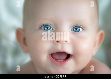 Close up di sorridere baby, 6 mesi di età che mostra gli occhi blu e due denti di bambino. Foto Stock