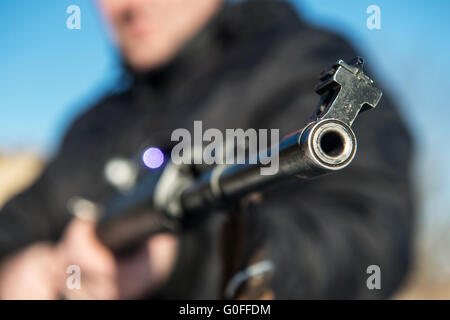 Un soldato o sniper tenendo la pistola con schermo virtuale proiezione e mirando in foresta Foto Stock