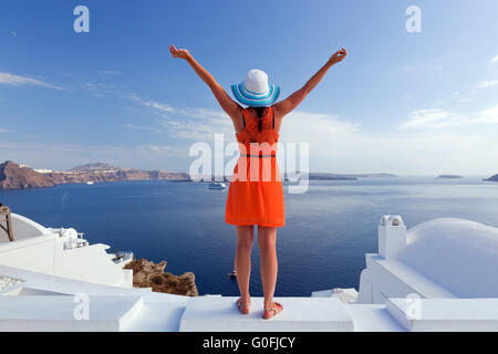 Donna felice nel cappello per il sole godendo le vacanze sull'isola di Santorini Foto Stock
