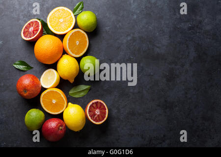 Fresche e mature agrumi. I Limoni e limette e le arance in pietra scura sullo sfondo. Vista da sopra con lo spazio di copia Foto Stock