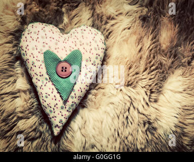 Vintage fatti a mano cuore di peluche cuscino sul morbido manto Foto Stock