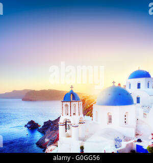 La cittadina di Oia a Santorini Grecia al tramonto. Tradizionale e famose case bianche e chiese con le cupole blu sulla Caldera Foto Stock