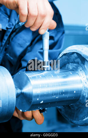 Lavoratore di misurazione industriale sulla macchina di tornitura. L'industria Foto Stock