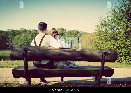 Coppia giovane in amore seduta su una panchina nel parco. Vintage Foto Stock