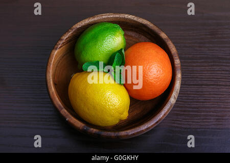 Mound gli agrumi in piatto di legno macro Foto Stock