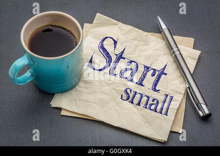 Avviare piccoli consigli - scrittura su un tovagliolo con tazza di caffè contro di ardesia grigia sullo sfondo di pietra Foto Stock