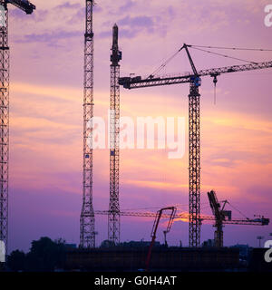 Sagome di gru edili sul sito di costruzione al tramonto, Francia, Europa Foto Stock