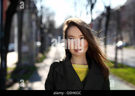 Bella donna asiatica con maglione giallo e rivestimento di oliva camminando sulla strada Foto Stock