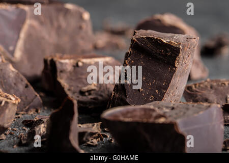 Il cioccolato. Cioccolato nero. Un paio di cubetti di cioccolato nero. Aggiungete pezzetti di cioccolato. Barra di cioccolato pezzi. Foto Stock
