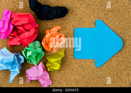 Colorata carta stropicciata su sfondo di sughero con carta bianca nota in forma di freccia, copia dello spazio disponibile Foto Stock