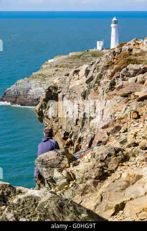 Gogarth falesie costiere con scalatore di mare al di sopra e al di là del faro. Stack del sud a Isola Santa Isola di Anglesey nel Galles REGNO UNITO Foto Stock