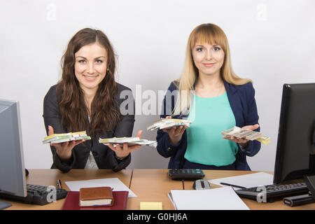 Ufficio di due membri del personale al tavolo sono in possesso di un pacco di denaro Foto Stock