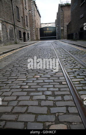 Originale di strade acciottolate al di fuori del Magazzino Guinness Brewery in Dublino Irlanda con il vecchio tram linee Foto Stock