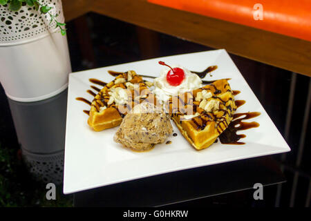 Frittelle dolci con salsa di cioccolato e gelato cioccolato sulla tabella Foto Stock