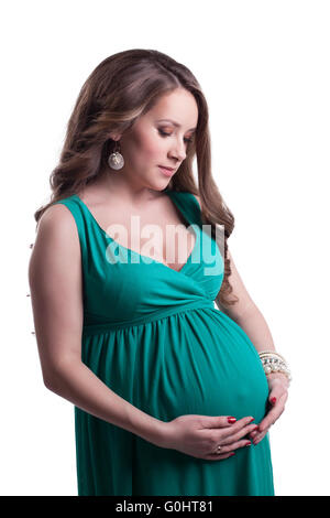 Bella donna incinta in posa in abito verde Foto Stock