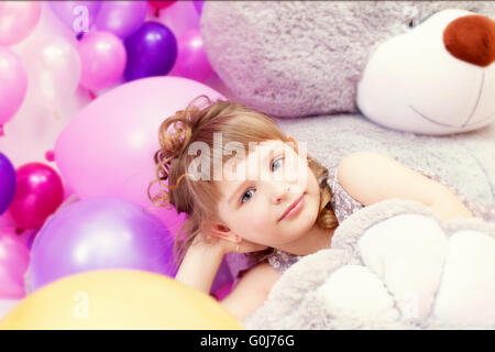 Colpo di colore grigio-eyed bambina giacente su Teddy bear Foto Stock