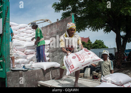 I lavoratori si muovono i sacchi di grano da un carrello per un carrello a Paotere Porto di Makassar, Indonesia. Foto Stock