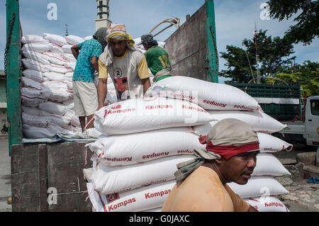 I lavoratori si muovono i sacchi di grano da un carrello per un carrello a Paotere Porto di Makassar, Indonesia. Foto Stock