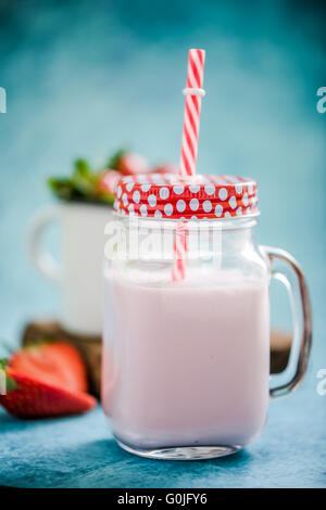 Frullato di fragole in vaso vintage con red spogliato di paglia blu su sfondo vivace Foto Stock