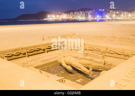 Crisi di rifugiati la scultura di sabbia, Las Palmas di Gran Canaria Isole Canarie Spagna, 1 maggio 2016. Scultore di sabbia/artista Etual Ojeda crea un stuning la scultura di sabbia sulla spiaggia cittadina e rende omaggio ai rifugiati che hanno perso la vita sul mare infido attraversamenti. L intricato lavoro mostra una persona galleggiante sull'acqua circondata da filo spinato con le parole 'immaginare non ci sono paesi" sopra la sua testa. Sotto i suoi piedi le parole "Homenaje a los refugiados del mundo". (Omaggio a dei rifugiati del mondo). Credito: Alan Dawson News/Alamy Live News Foto Stock