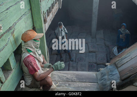 Lavoratori attendere all'interno dello scafo di una barca caricata con cemento a Paotere Porto di Makassar, Indonesia. Foto Stock