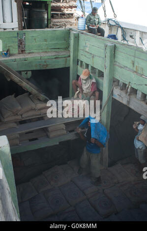 Lavoratori attendere all'interno dello scafo di una barca caricata con cemento a Paotere Porto di Makassar, Indonesia. Foto Stock