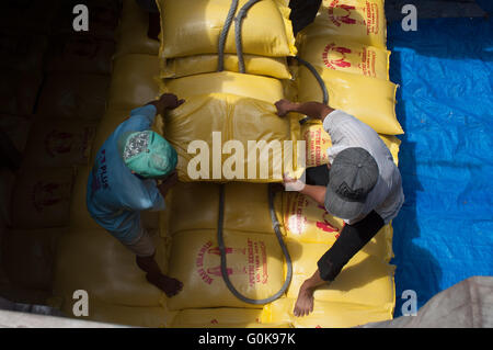 Lavoratori caricati sacchi di cemento nello scafo di una imbarcazione a Paotere Porto di Makassar, Indonesia. Foto Stock