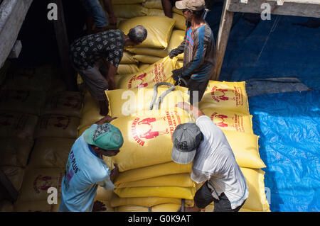 Lavoratori caricati sacchi di cemento nello scafo di una imbarcazione a Paotere Porto di Makassar, Indonesia. Foto Stock